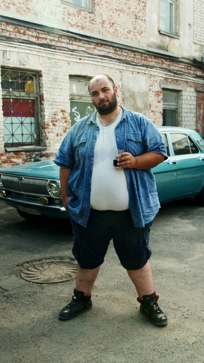 Mr. Big, an undercover cop, standing in an alley in front of classic car