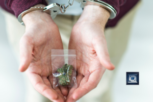 two hands handcuffed while holding cannabis