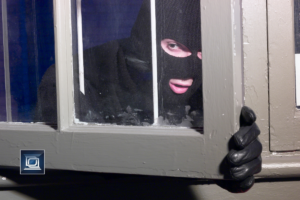 burglar breaking in through window during home invasion